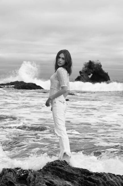 Black and White Photo of a Woman Standing on a Beach 