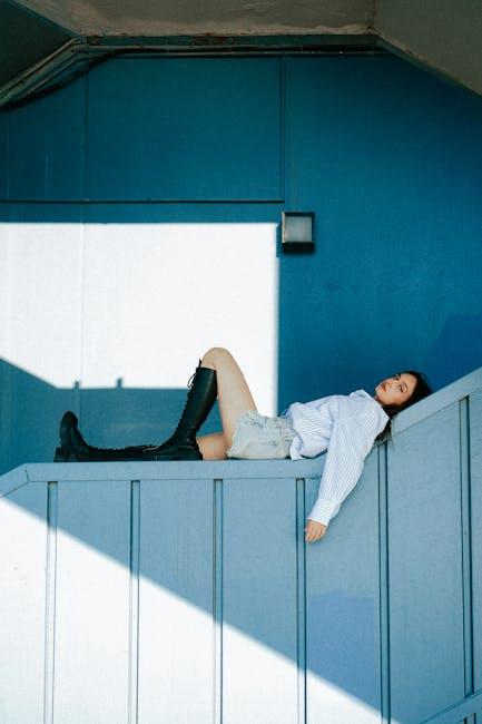 Young Woman in Striped Shirt and Boots Lying on the Wall 