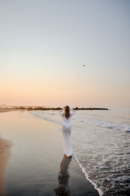 A woman in a white dress standing on the beach