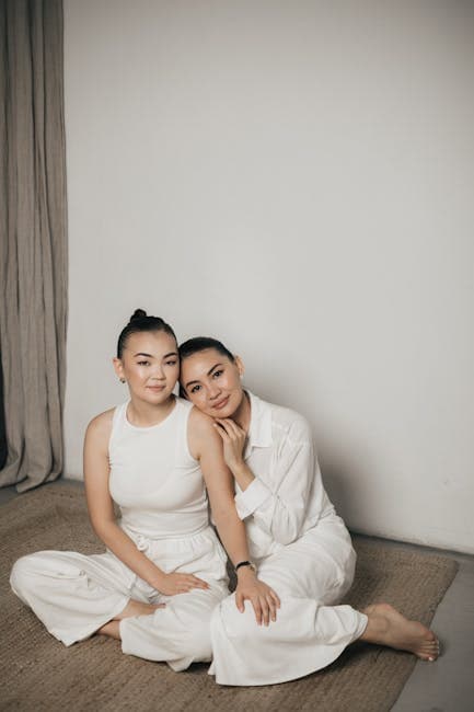 Women in White Clothing Sitting Together on Rug