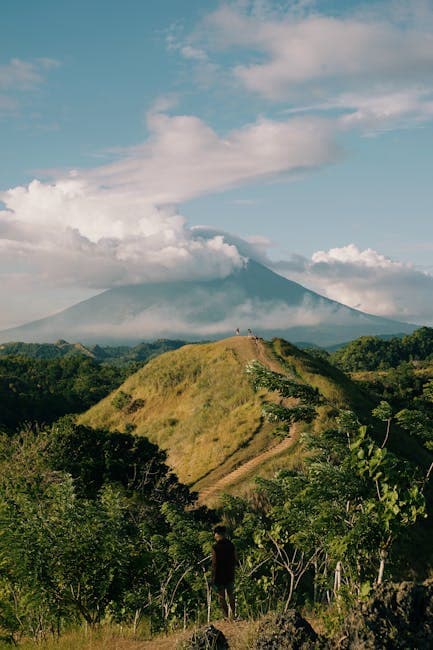 A person standing on a hill overlooking a volcano