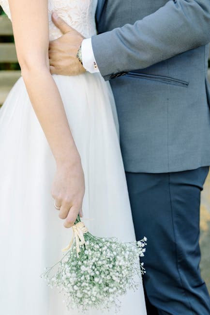 A bride and groom are holding a bouquet of flowers