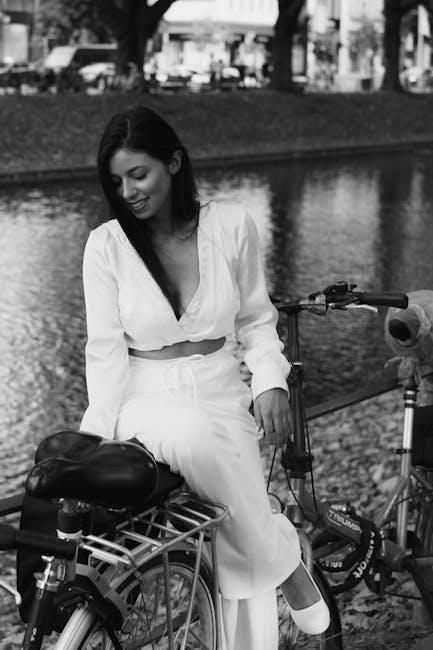 A woman sitting on a bike next to a river