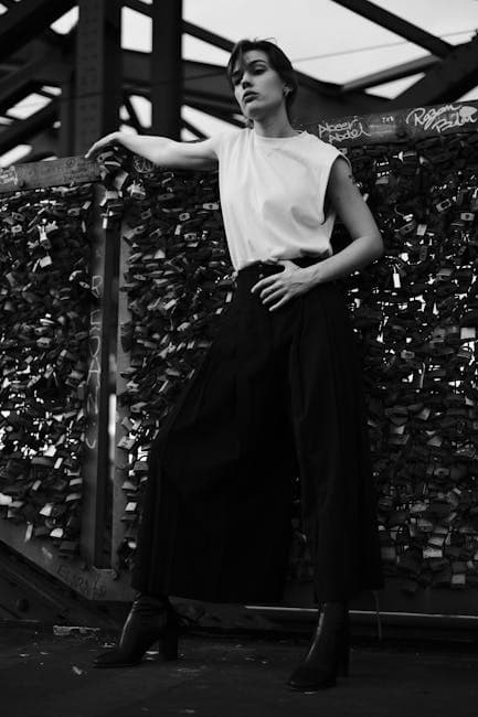 A woman in black and white is posing on a bridge