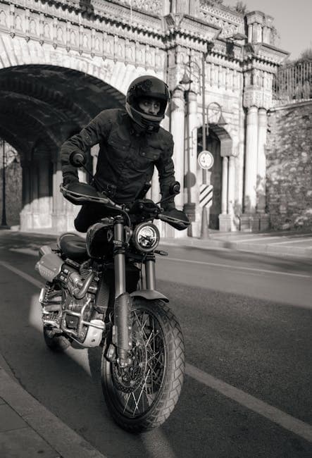 A man on a motorcycle rides under a bridge