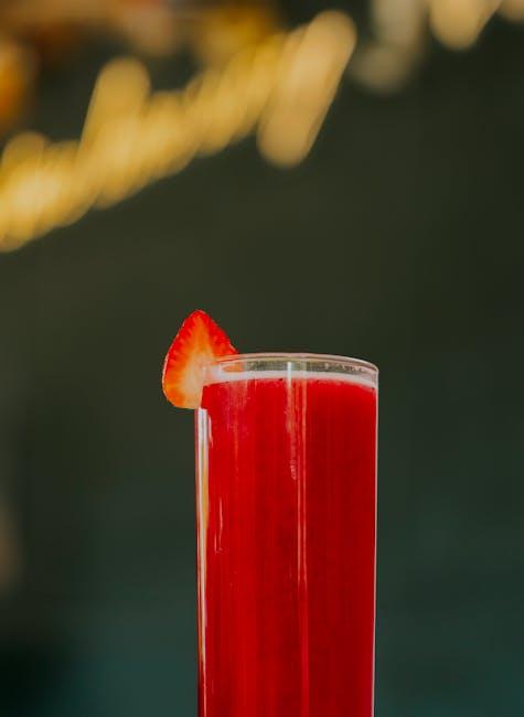 A red drink with a strawberry garnish on top