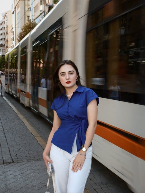 A woman in white pants and blue shirt standing on a street