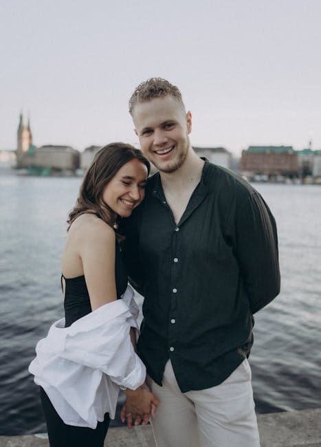 A couple posing for a photo by the water