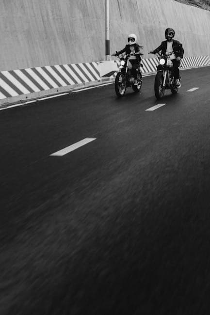 Two people riding motorcycles down a road