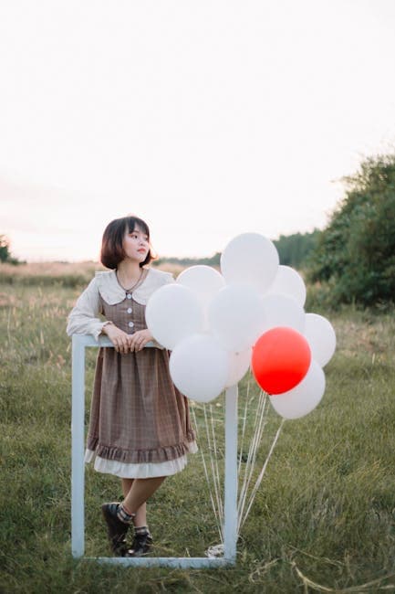 Woman in Dress Standing with Balloons at Field