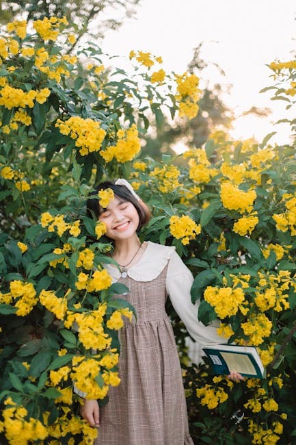 Portrait of Smiling Woman in Dress Standing among Yellow Flowers