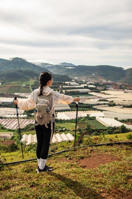 A woman with hiking poles standing on a hill