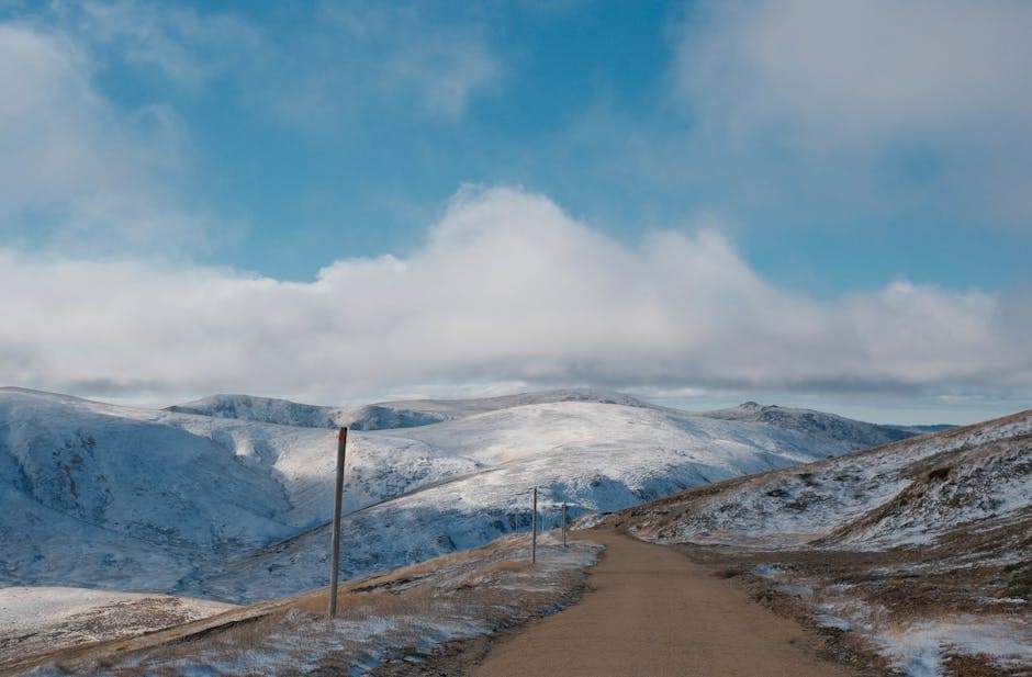 A dirt road with snow on it and a blue sky