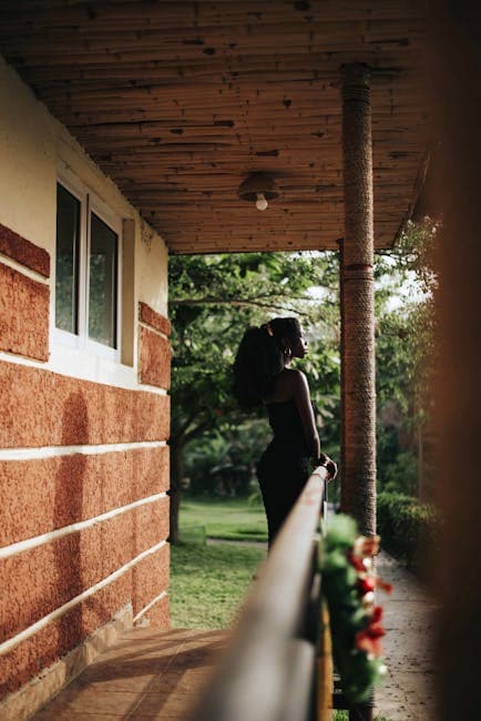 A woman standing on a porch looking out at the sun