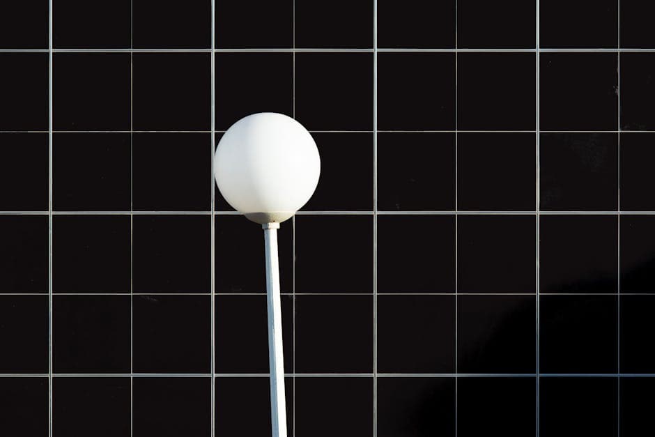 A white ball on a stick in front of a black tiled wall