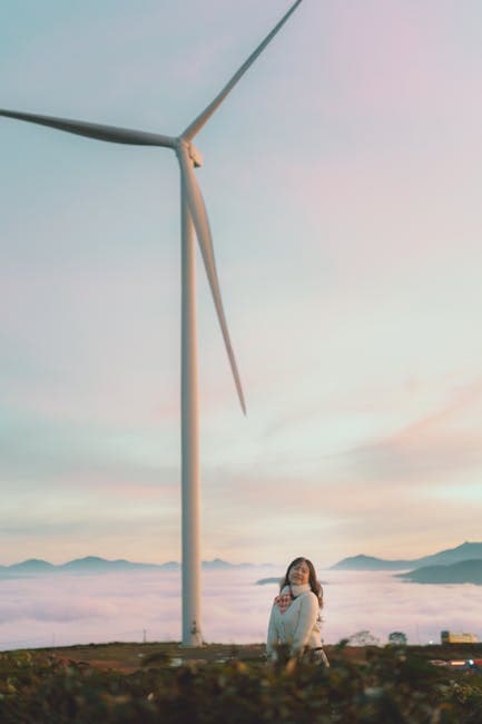 A woman sitting on a bench in front of a wind turbine