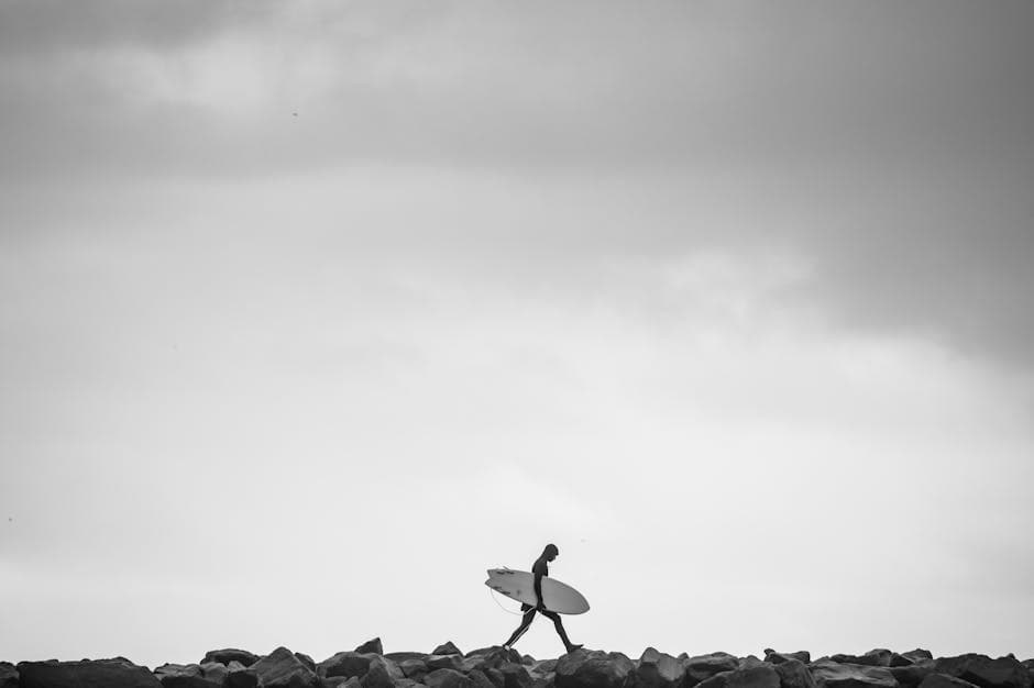 A man walking with a surfboard on a beach