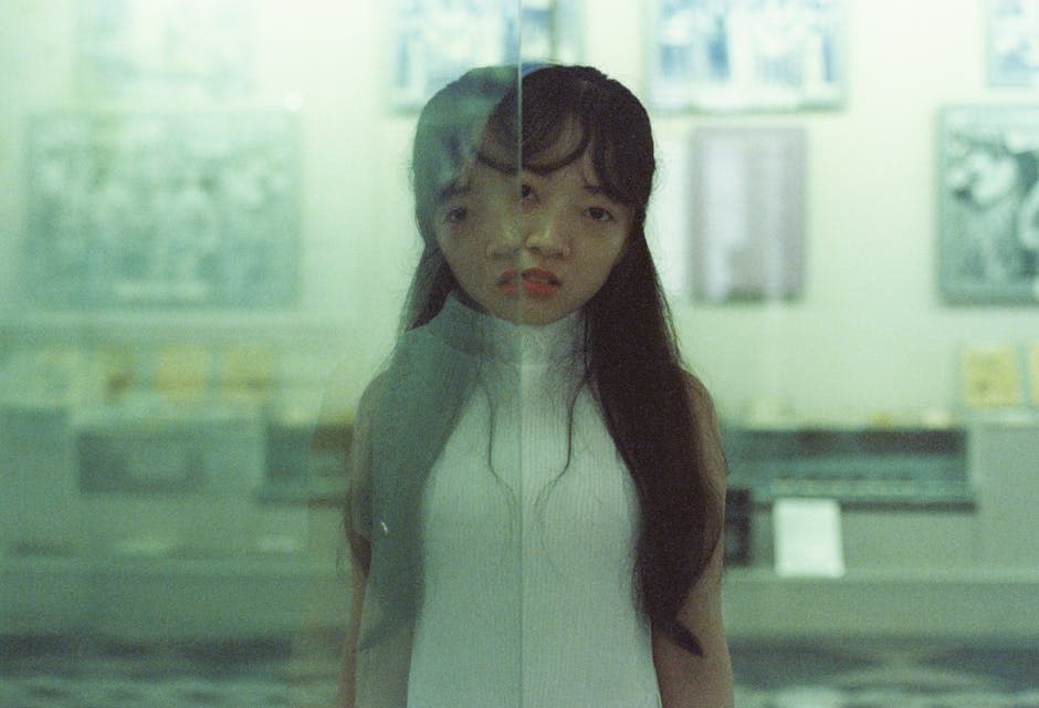 A woman in white dress standing in front of a glass wall