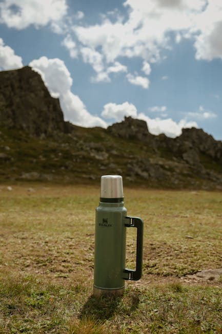 A green thermos sitting on top of a grassy field