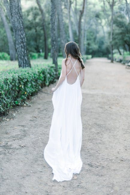 A woman in a white dress walking down a path