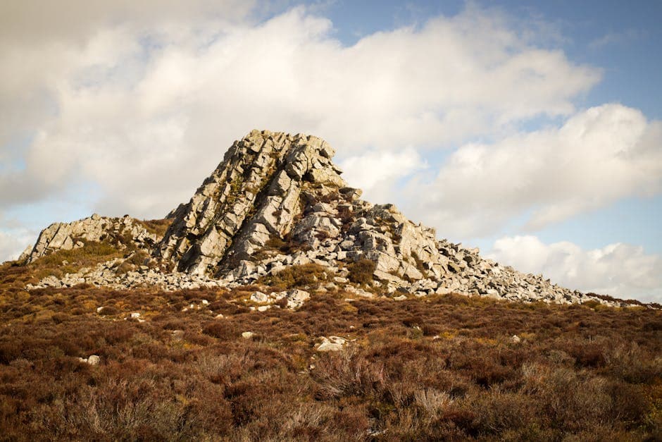 A large rock on a hill with a blue sky