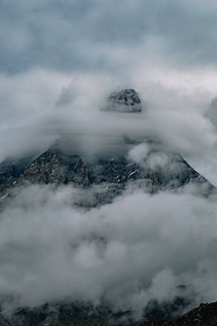 A mountain covered in clouds with a dark sky