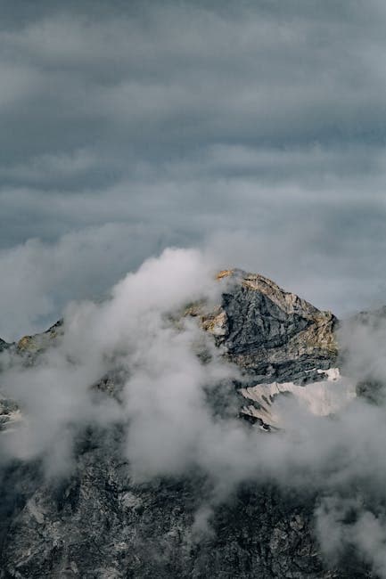 A mountain covered in clouds with a cloudy sky