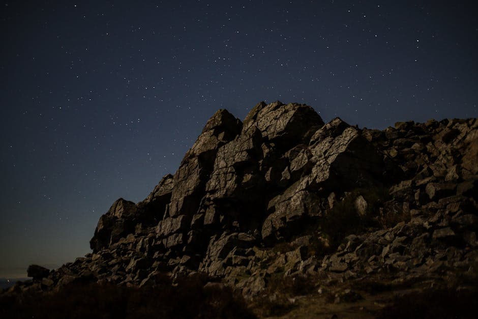 Stars over Rocks on Hill at Night