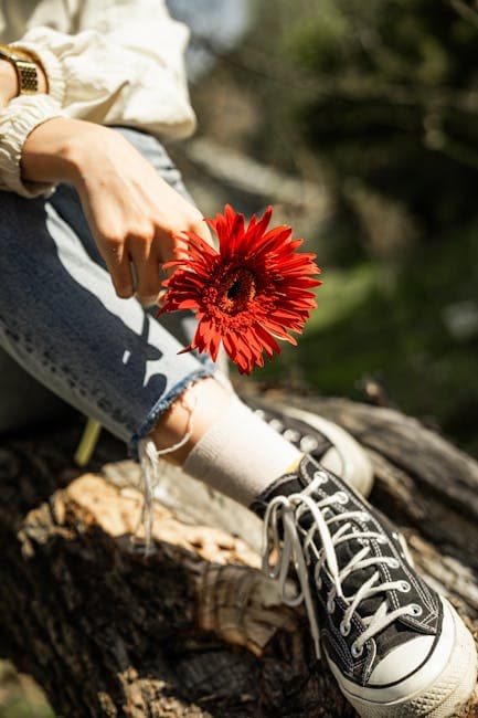 A woman's feet are sitting on a log with a flower