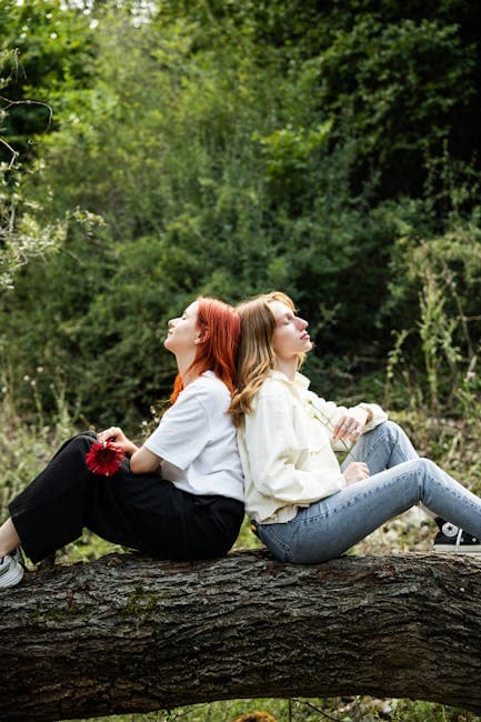 Two girls sitting on a tree branch