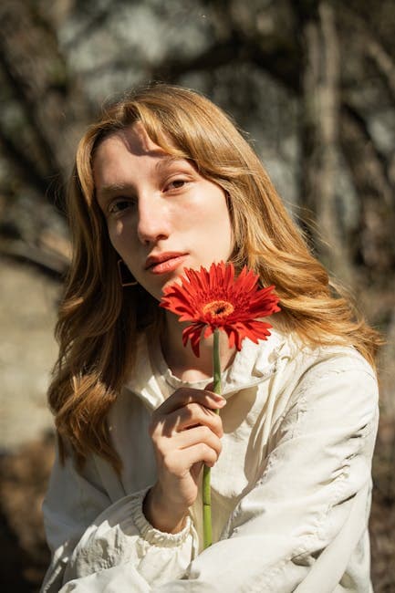 A woman holding a red flower in her hand