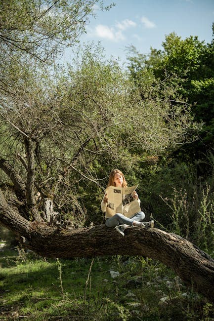 A woman sitting on a tree branch with a guitar