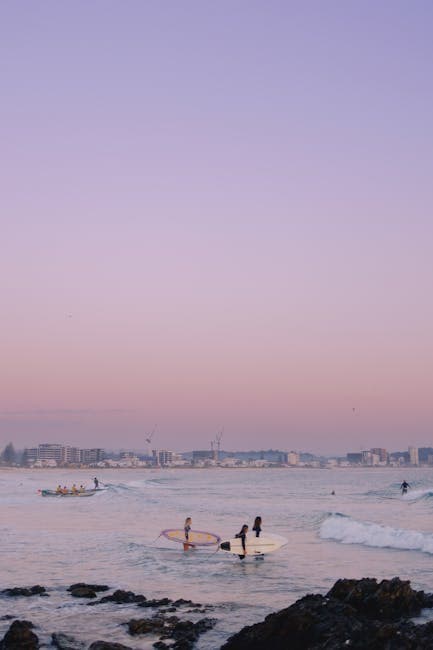 People with Surfboards Walking on the Beach at Sunset