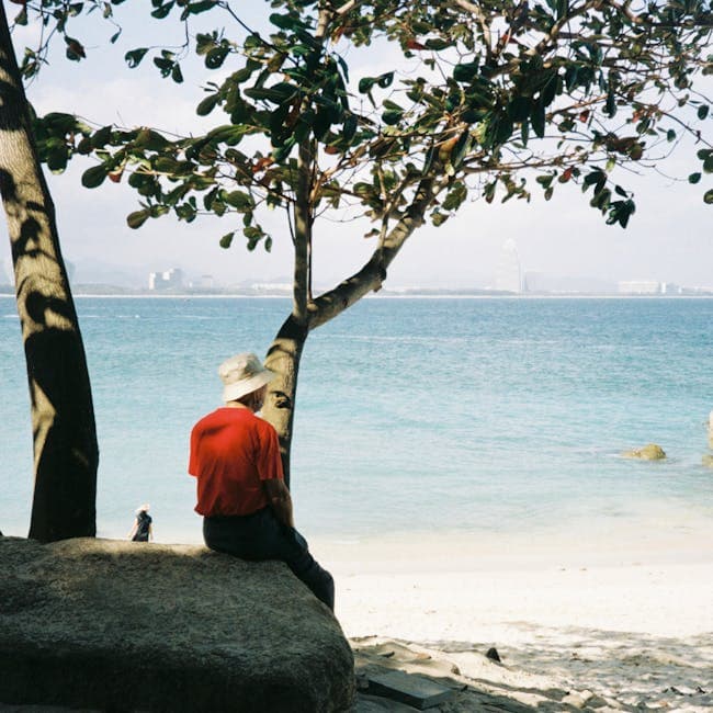 A man sitting on a rock by the water