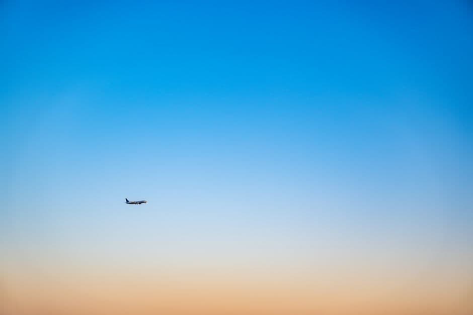 Airplane in clear blue and orange sky at sunset