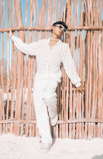 Stylish Man in White Outfit Against Rustic Fence