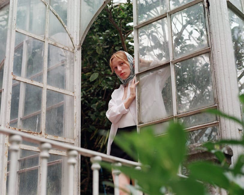 Woman in White Shirt Looking Out from Glass Door