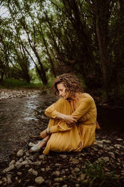 Contemplative woman looking down at flowing creek